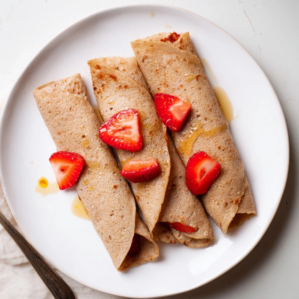Light tender oatmeal crepe folded with yogurt filling and sliced banana on white plate