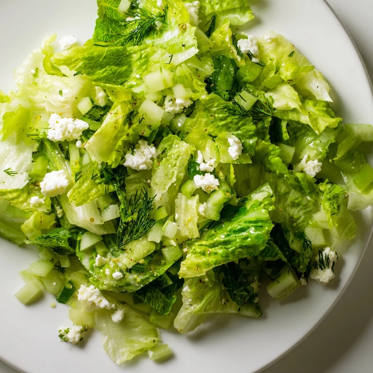 Fresh Maroulosalata Greek salad with crisp romaine lettuce, dill, mint, and bright lemon dressing in a white bowl