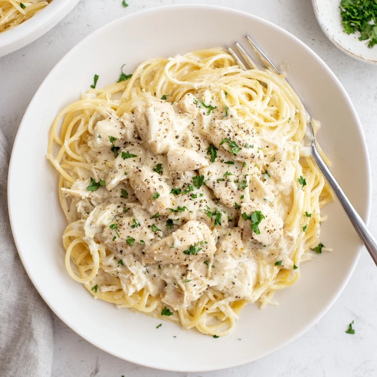 Slow-cooked chicken breasts in rich Italian cream sauce served over light pasta strands