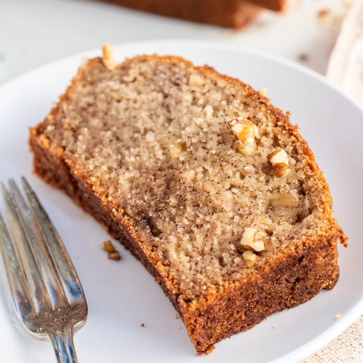 Homemade gluten-free keto banana bread topped with pecans and served on white plate