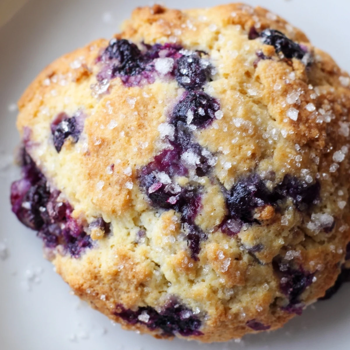 Flaky buttery blueberry biscuits stacked high with fresh berries and honey drizzle alongside