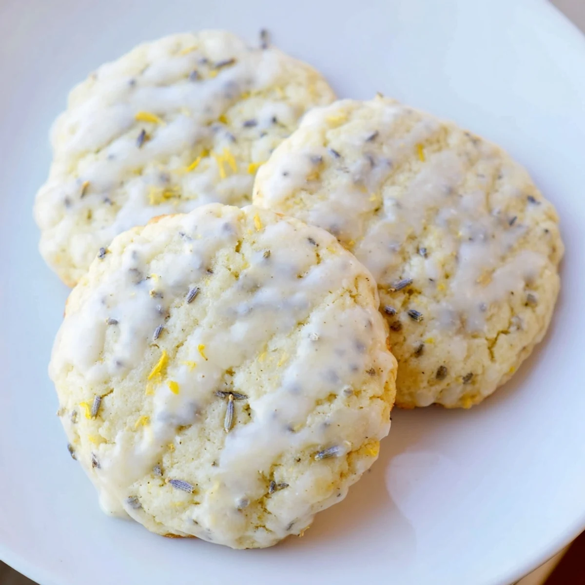 Soft Lemon Lavender Cookies with golden edges arranged on a rustic white ceramic plate