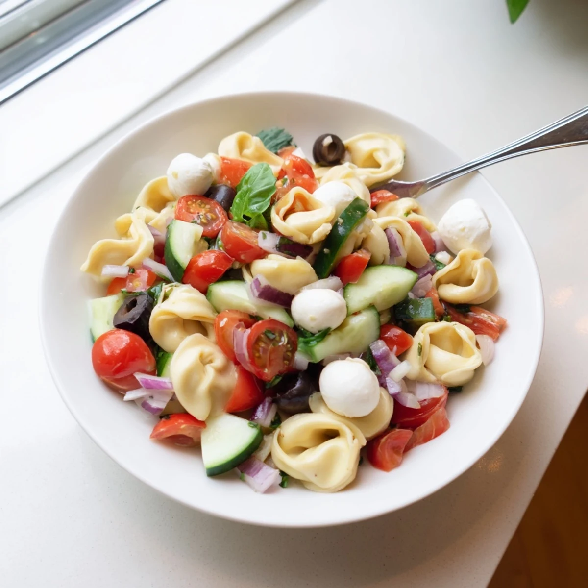 Creamy tortellini pasta salad loaded with colorful vegetables and zesty Italian dressing in a bowl