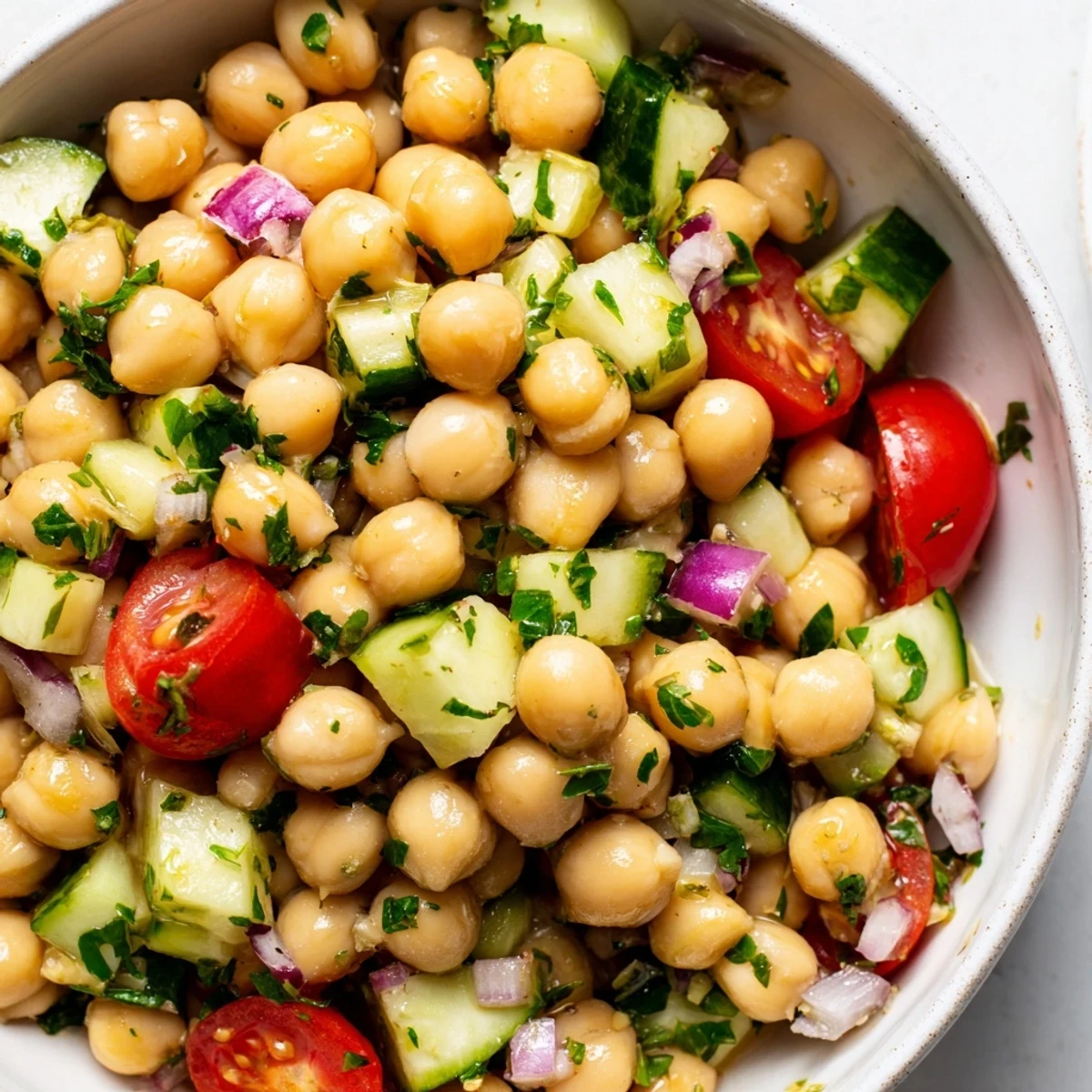 Chickpea cucumber salad in a white bowl with fresh herbs and bright lemon dressing