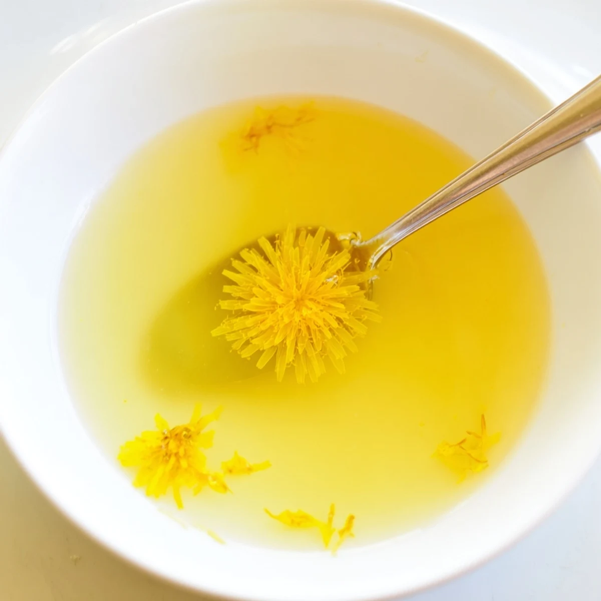 Homemade fresh dandelion jelly spread thick over a flaky scone with soft cheese