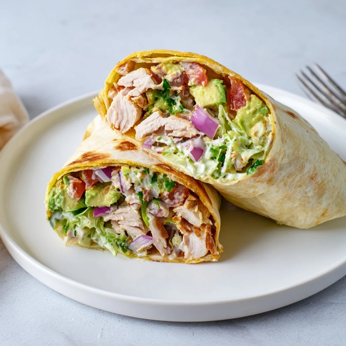 Sliced Chicken Avocado Ranch Burritos on plate, fresh cilantro and tomato garnish
