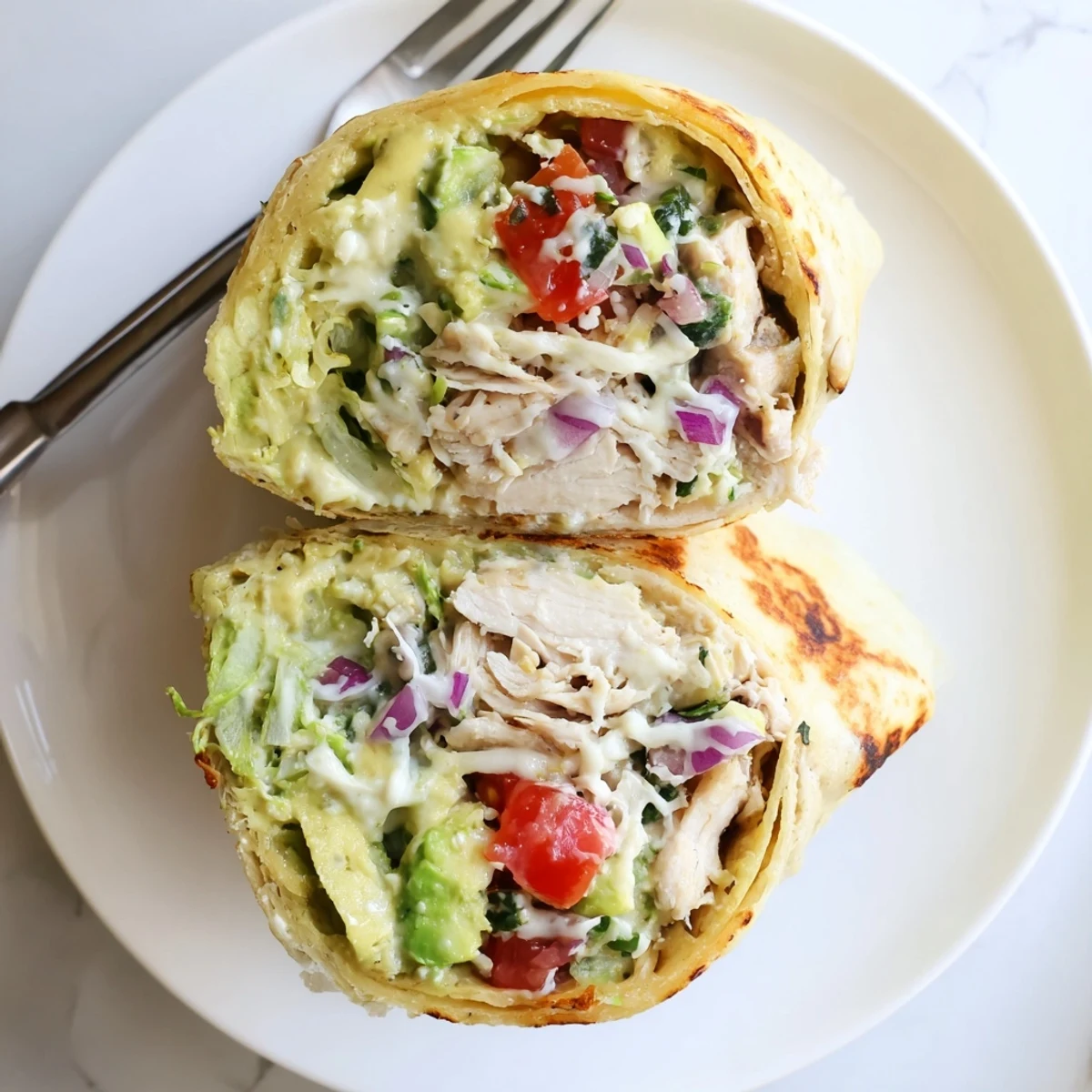 Warm Chicken Avocado Ranch Burritos halved, juicy chicken visible, lime wedge nearby