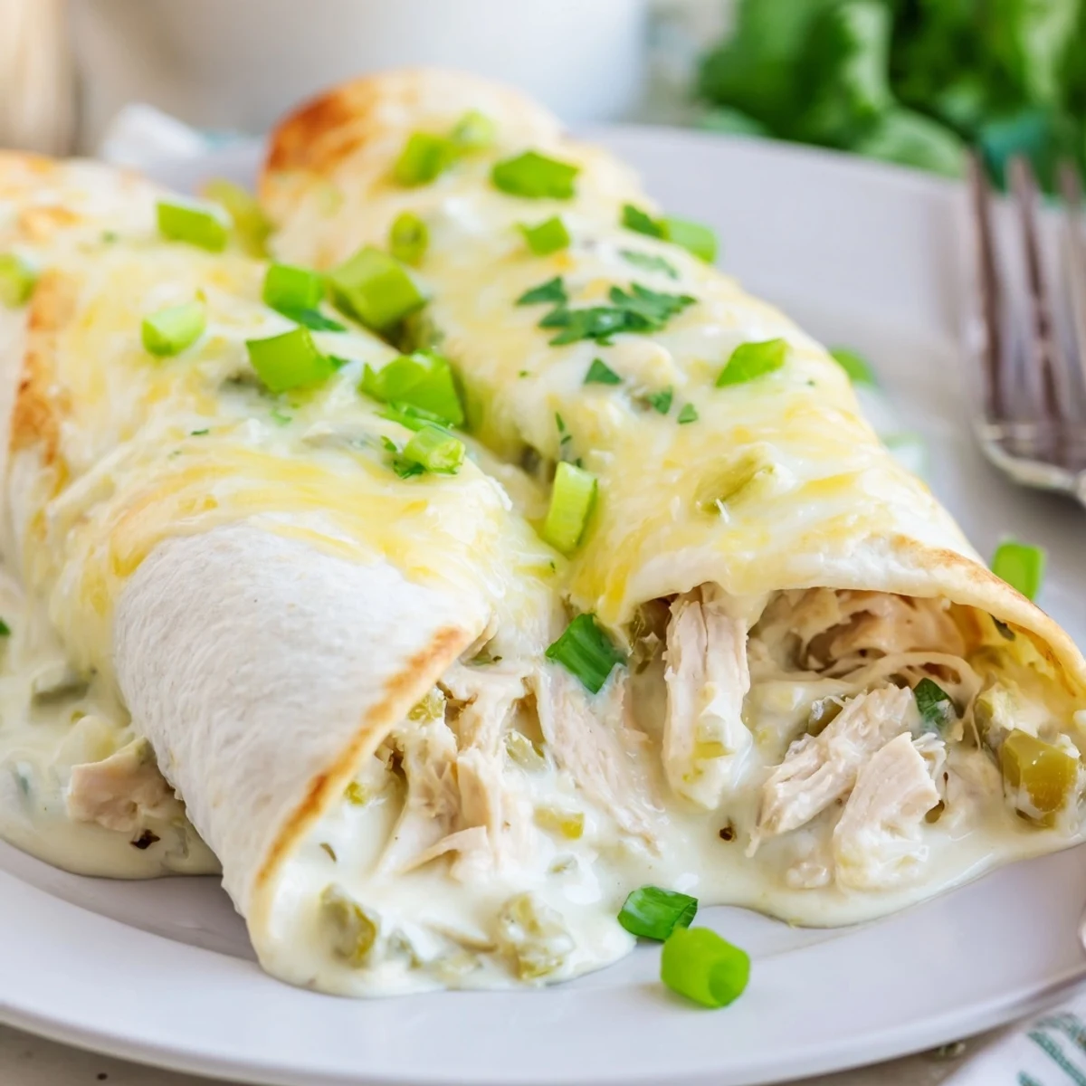 White Rotisserie Chicken Enchiladas bubbling with creamy sauce, melted cheese and cilantro