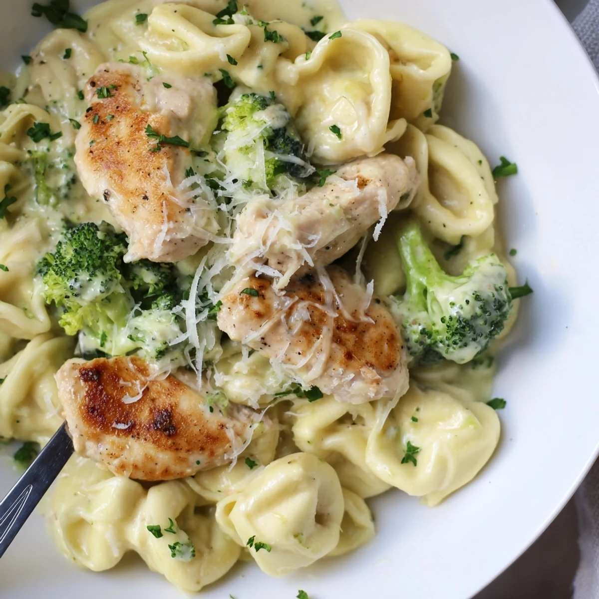 Creamy Garlic Parmesan Tortellini Chicken Broccoli Recipe with golden chicken and steaming sauce.