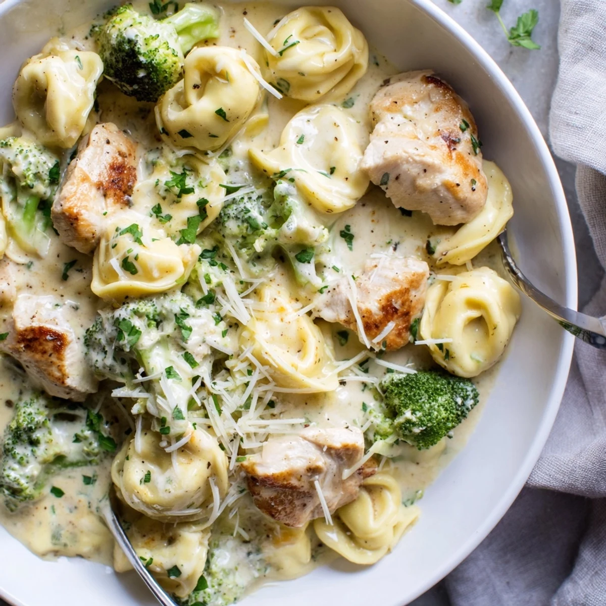 Spoon-ready bowl of Creamy Garlic Parmesan Tortellini Chicken Broccoli Recipe, fragrant garlic aroma.