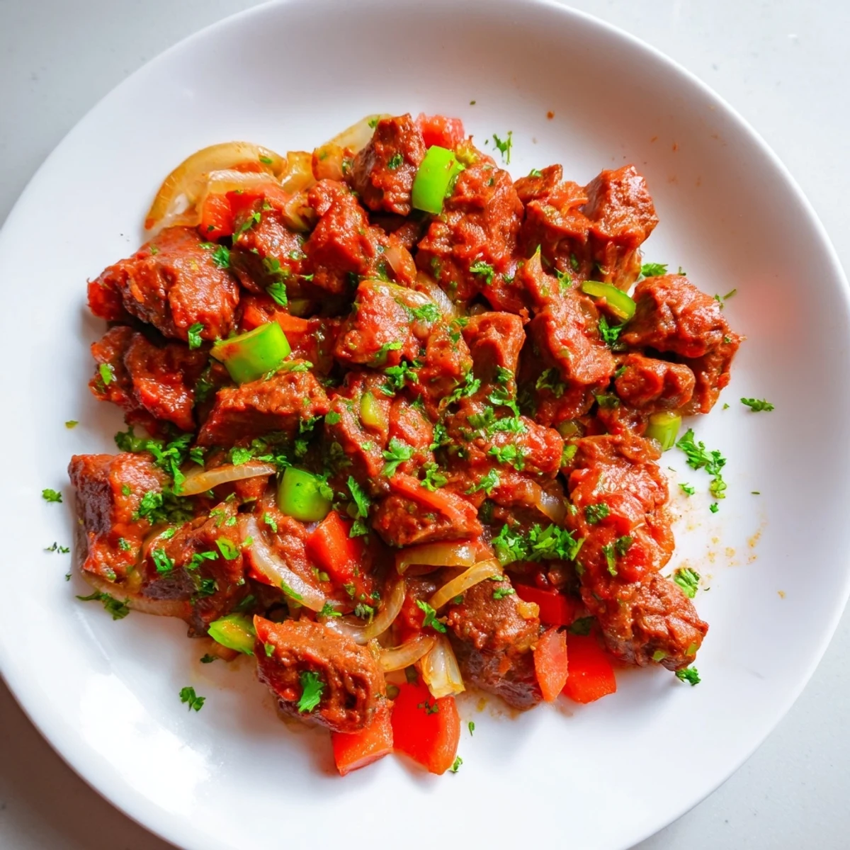 Tender Kenyan goat wet fry simmered in rich tomato onion sauce with fresh coriander garnish