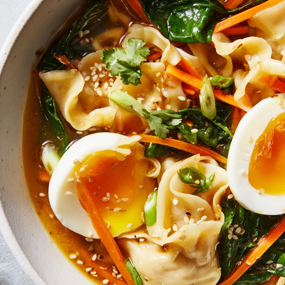 Comforting dumpling ramen bowl with creamy soft-boiled eggs, vibrant greens, and fragrant sesame-ginger broth