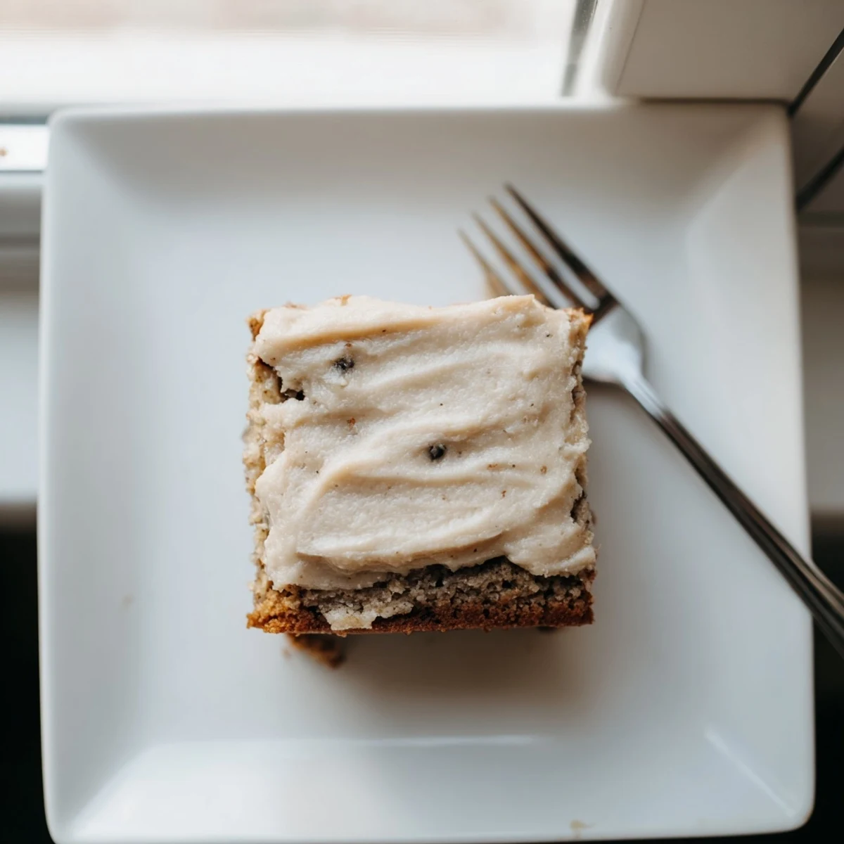 Thick banana bread brownies squares swirled with nutty brown butter frosting on plate
