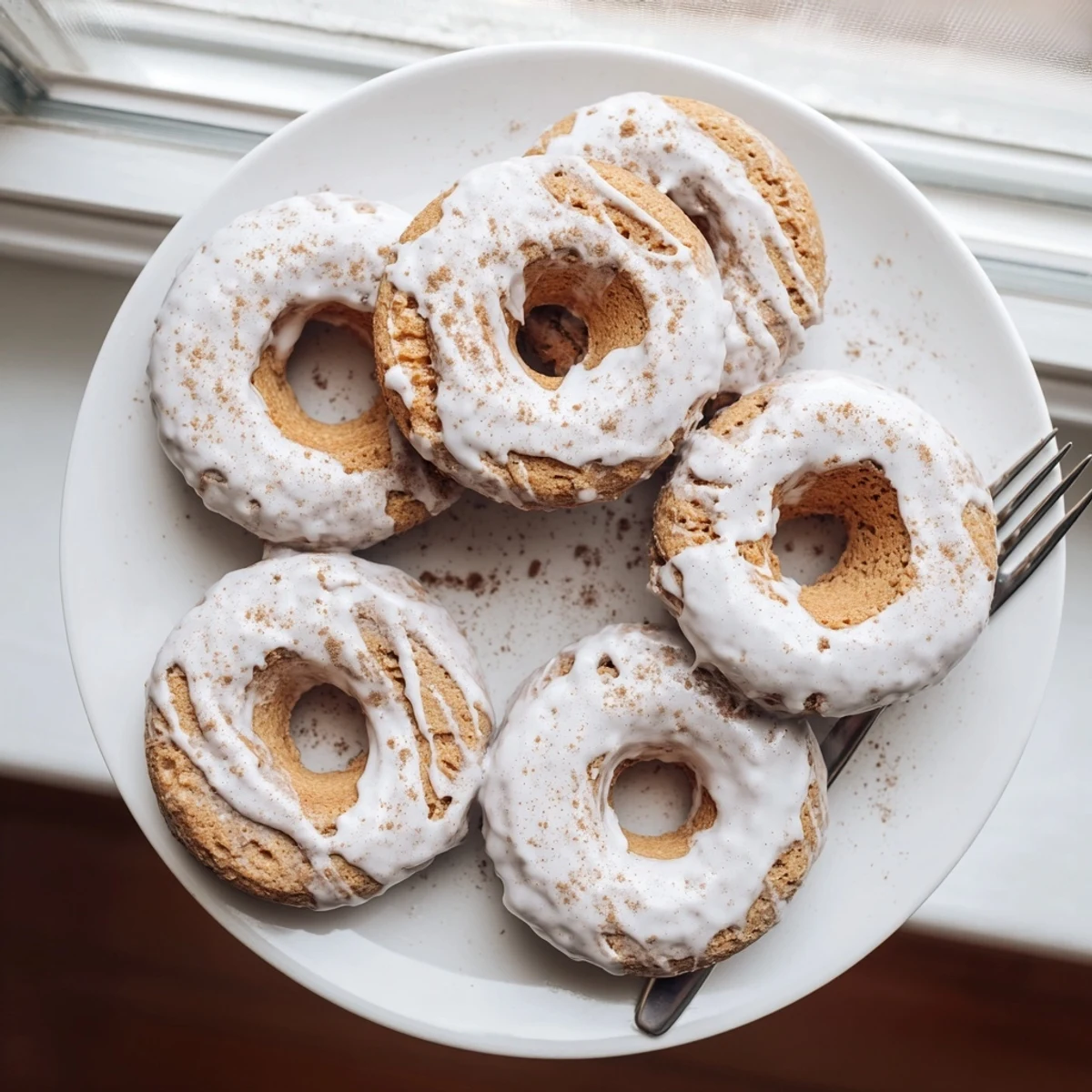 Golden brown banana bread donuts dusted with cinnamon sugar glaze on a wire cooling rack