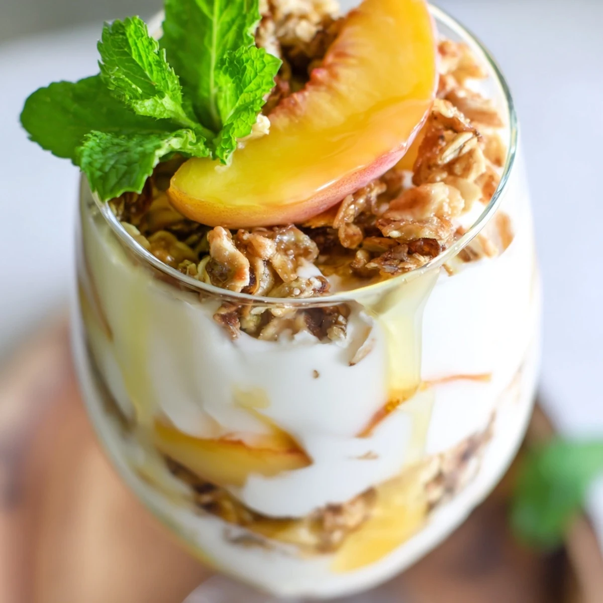 Sweet peach yogurt parfait delight layered with fresh peaches, creamy yogurt and crunchy granola in glass