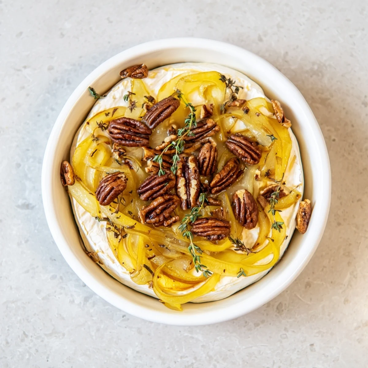 Creamy baked brie topped with golden caramelized onions and pecans, served with crackers