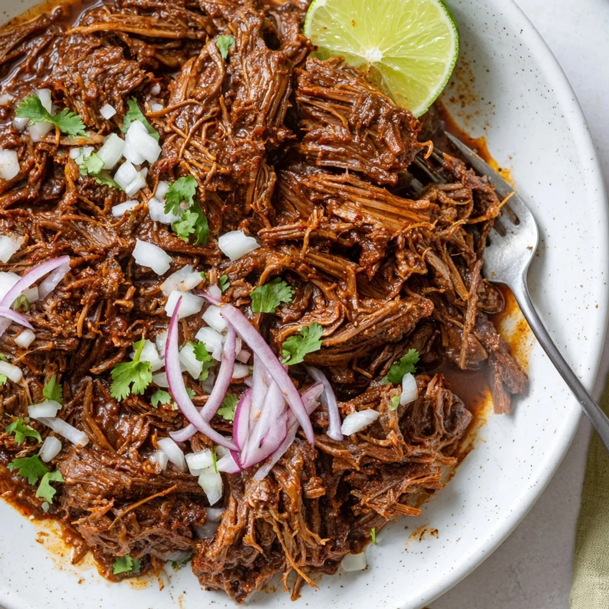 Shredded Slow Cooker Beef Barbacoa glistening with juices, perfect over rice bowls.