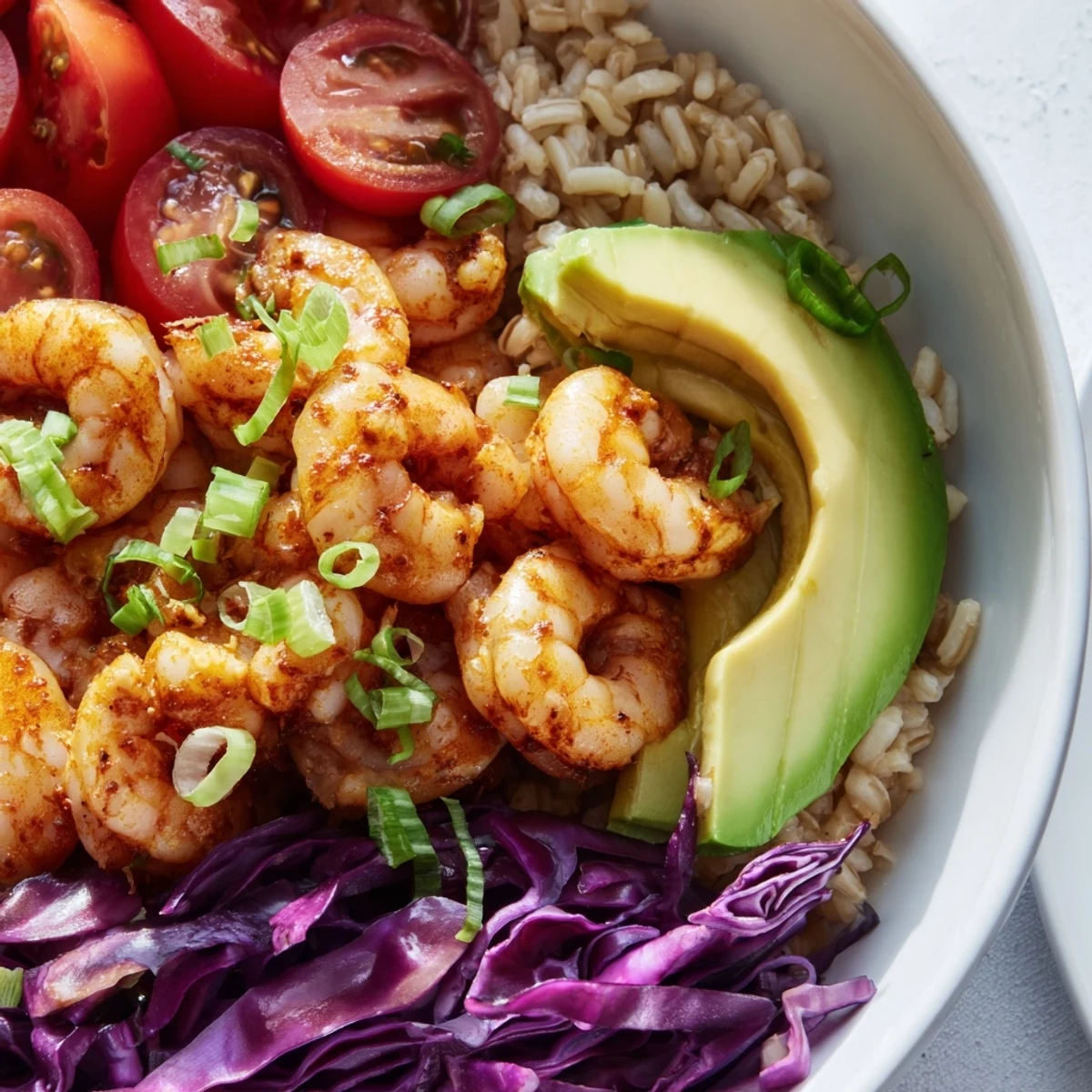 Vibrant shrimp grain bowl served in a rustic dish with juicy tomatoes and shredded cabbage