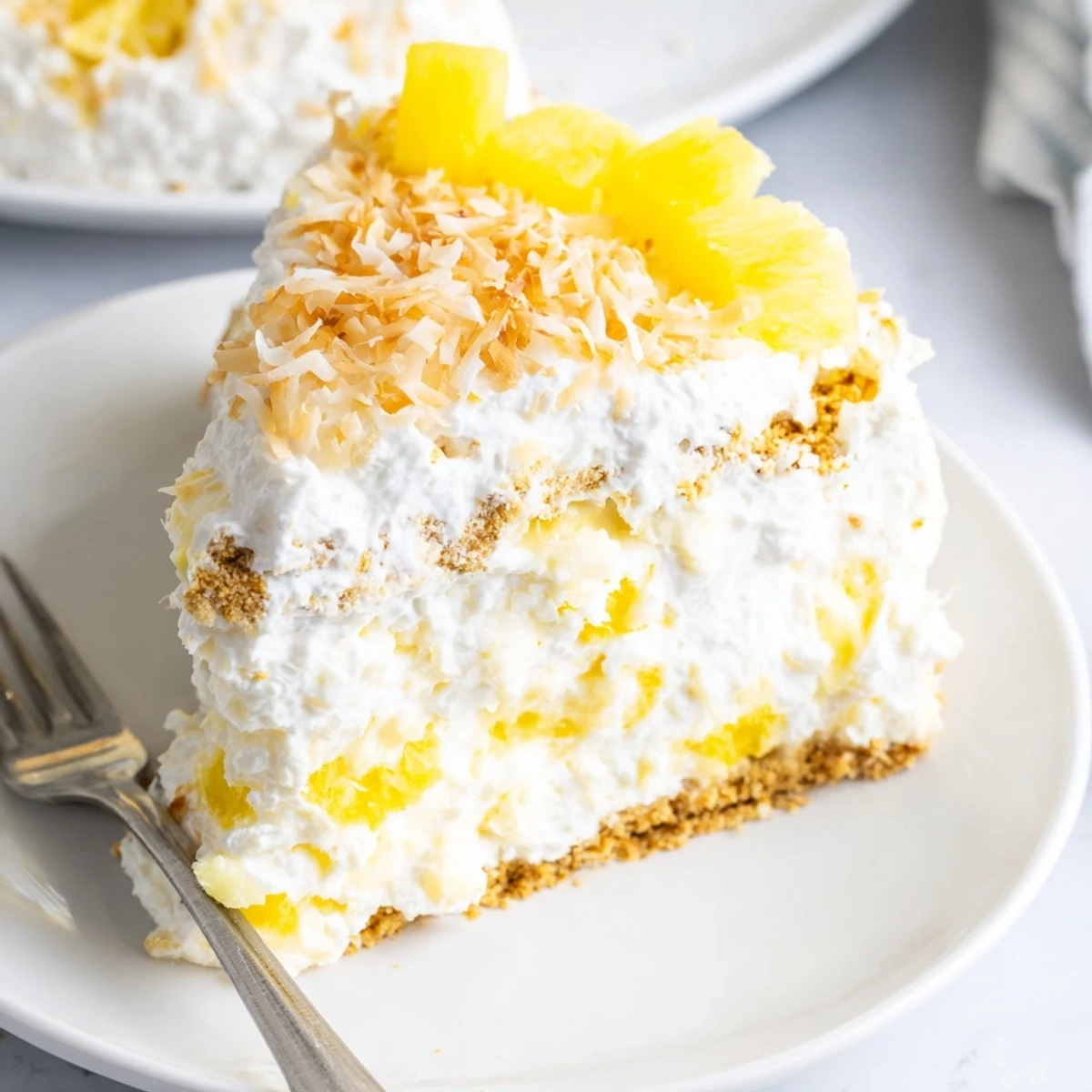 Creamy No Bake Pineapple Coconut Cream Cake sliced on a white dessert plate